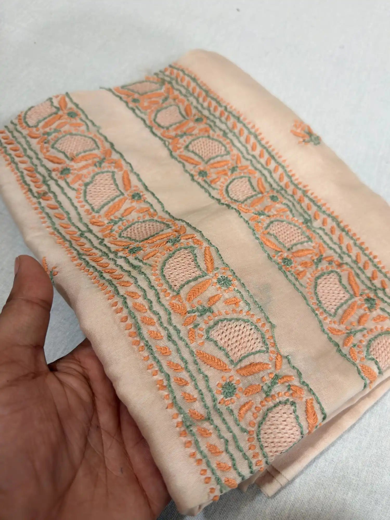Folded Peach Blush Chanderi Silk Lucknowi Chikankari kurta fabric featuring elegant peach and green embroidery.