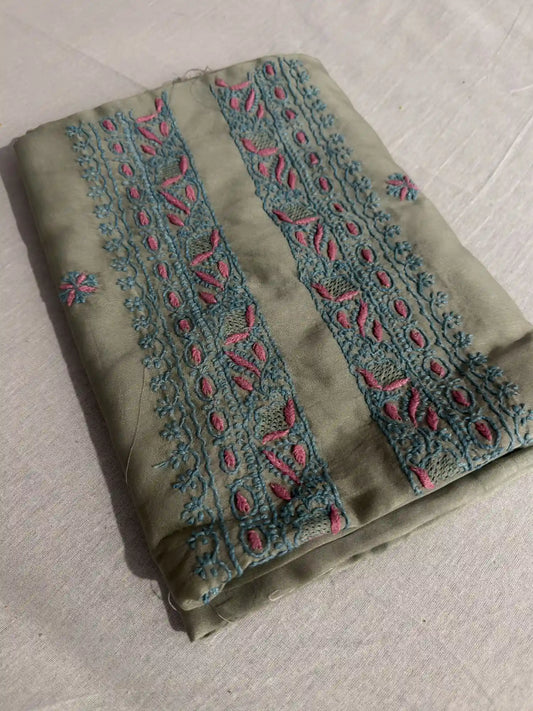 Folded Sage Green Chanderi Silk Lucknowi Chikankari kurta fabric featuring intricate turquoise and pink hand embroidery.