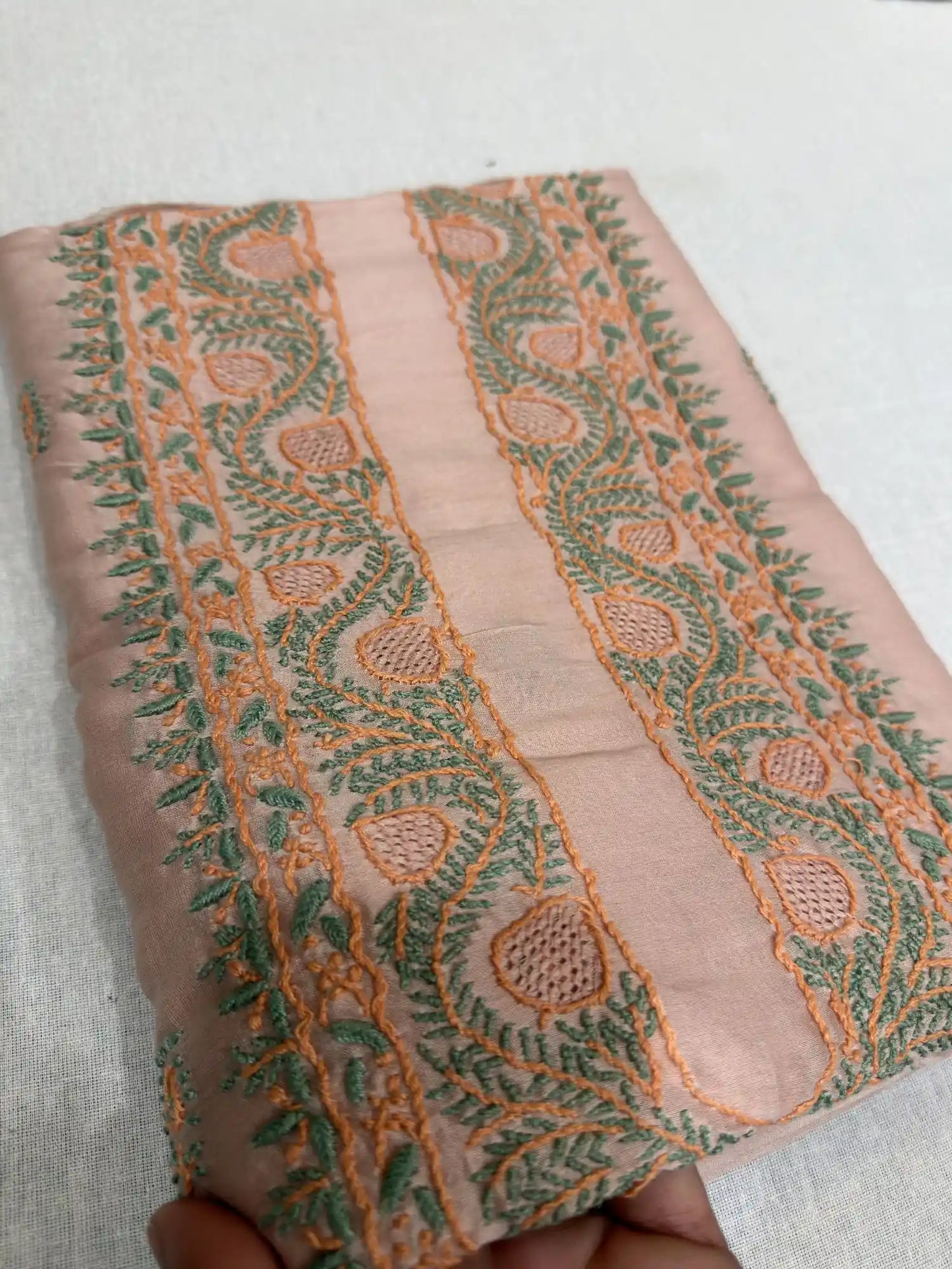Close-up of premium Peach Chanderi Silk fabric showcasing fine Lucknowi Chikankari embroidery and woven texture.