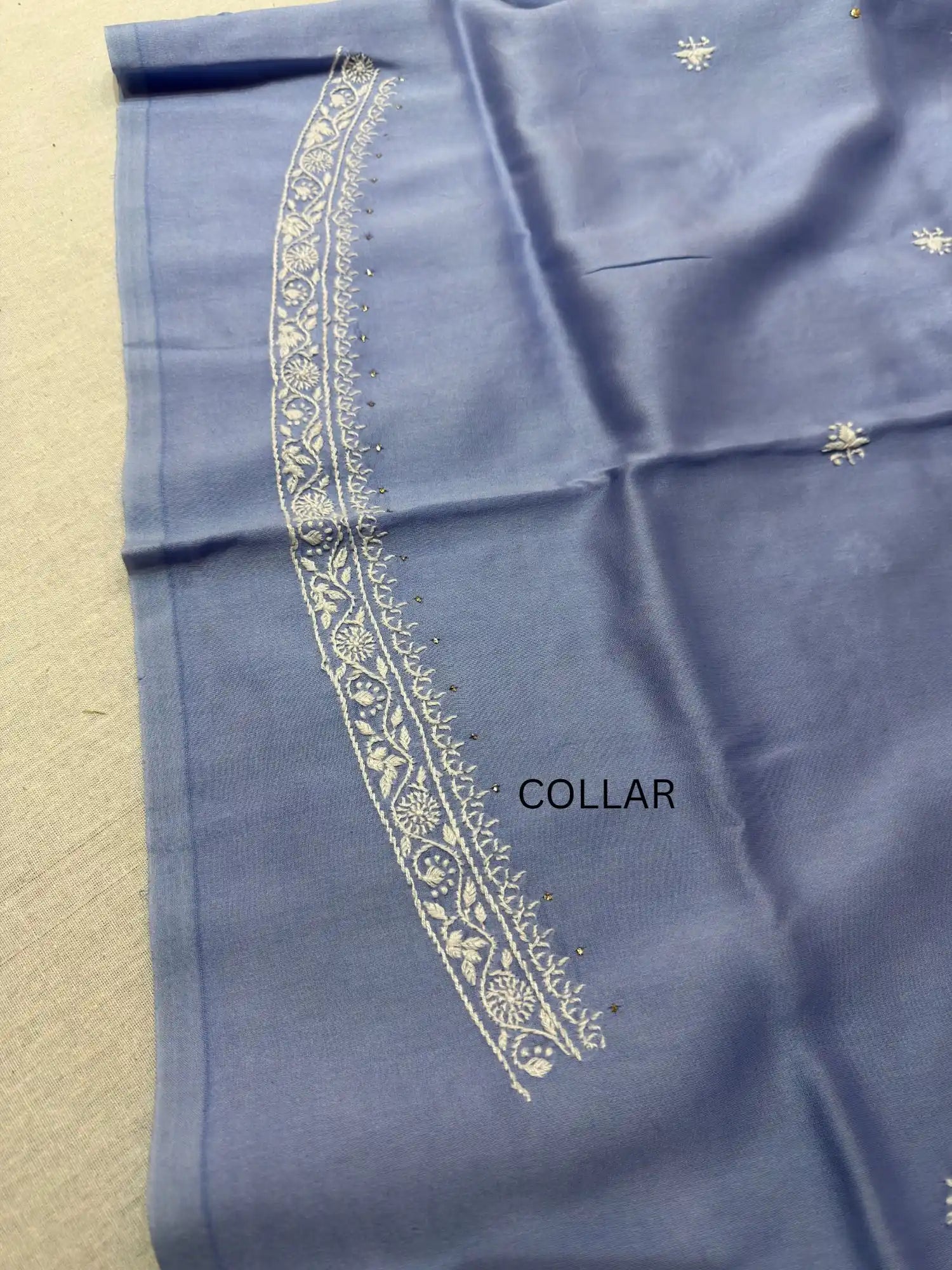 Detailed white Lucknowi Chikankari embroidery on the collar of Powder Blue linen kurta fabric.