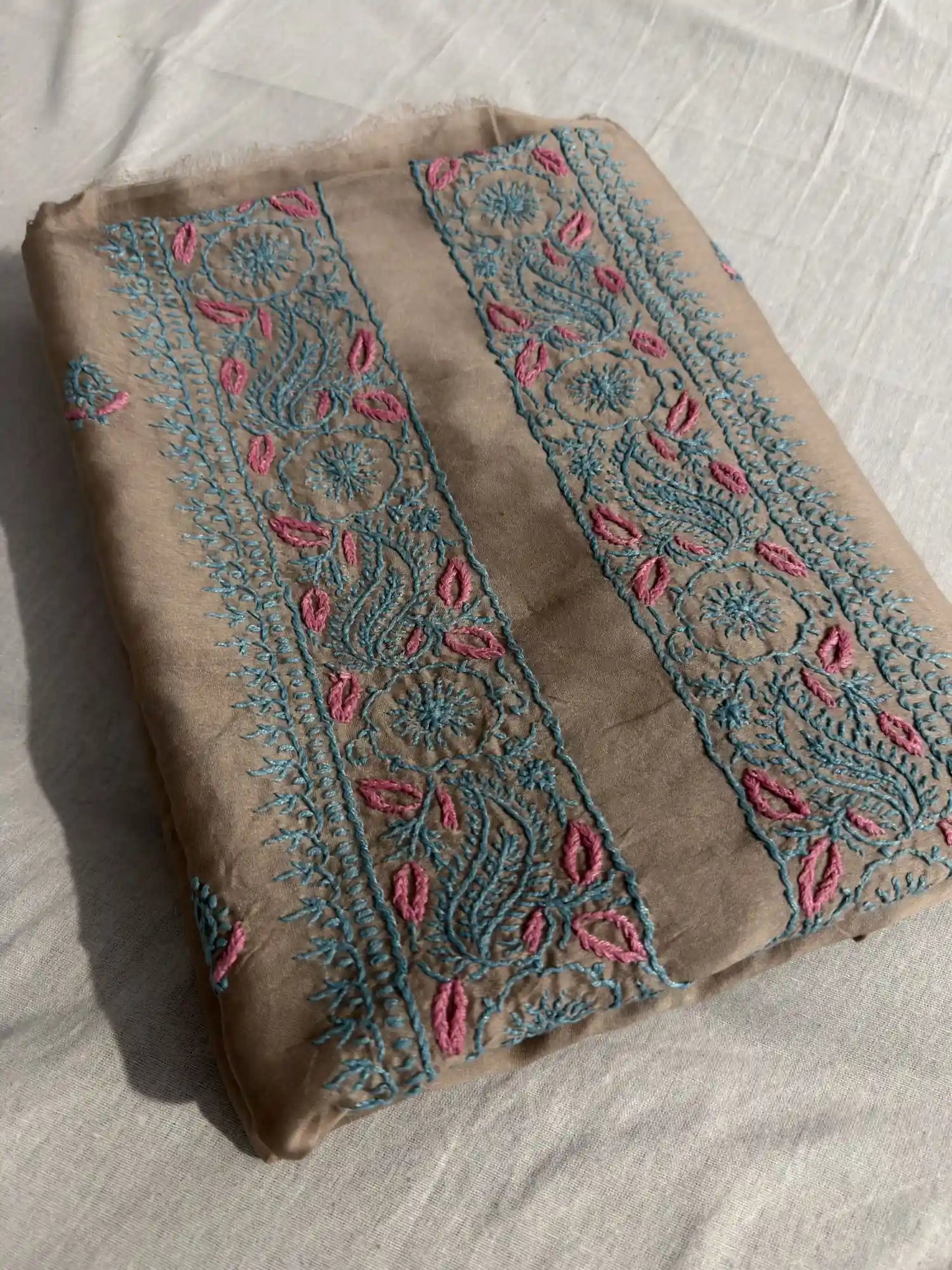 Folded Taupe Brown Chanderi Silk Lucknowi Chikankari kurta fabric showcasing elegant turquoise and pink embroidery.