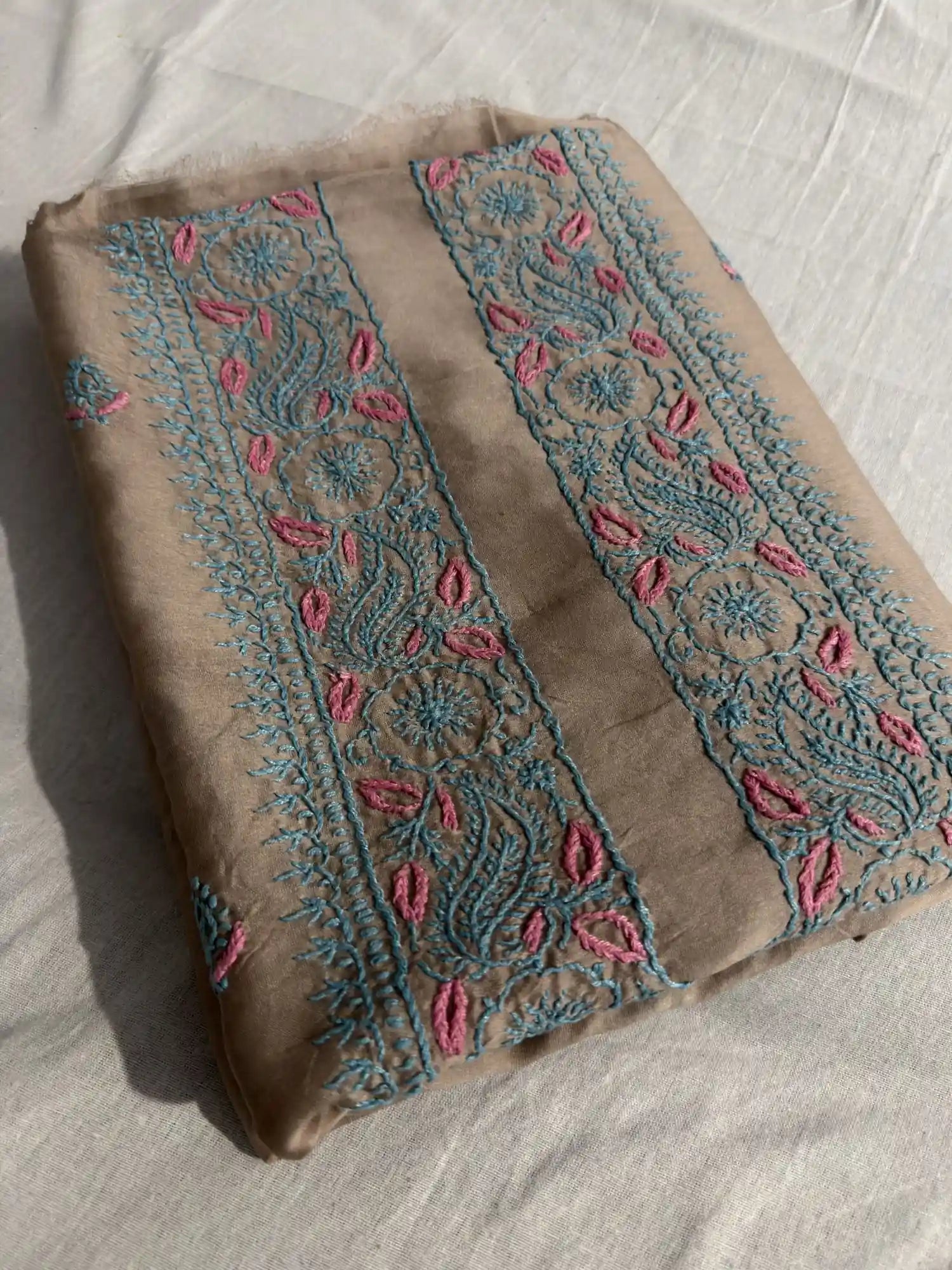 Folded Taupe Brown Chanderi Silk Lucknowi Chikankari kurta fabric showcasing elegant turquoise and pink embroidery.